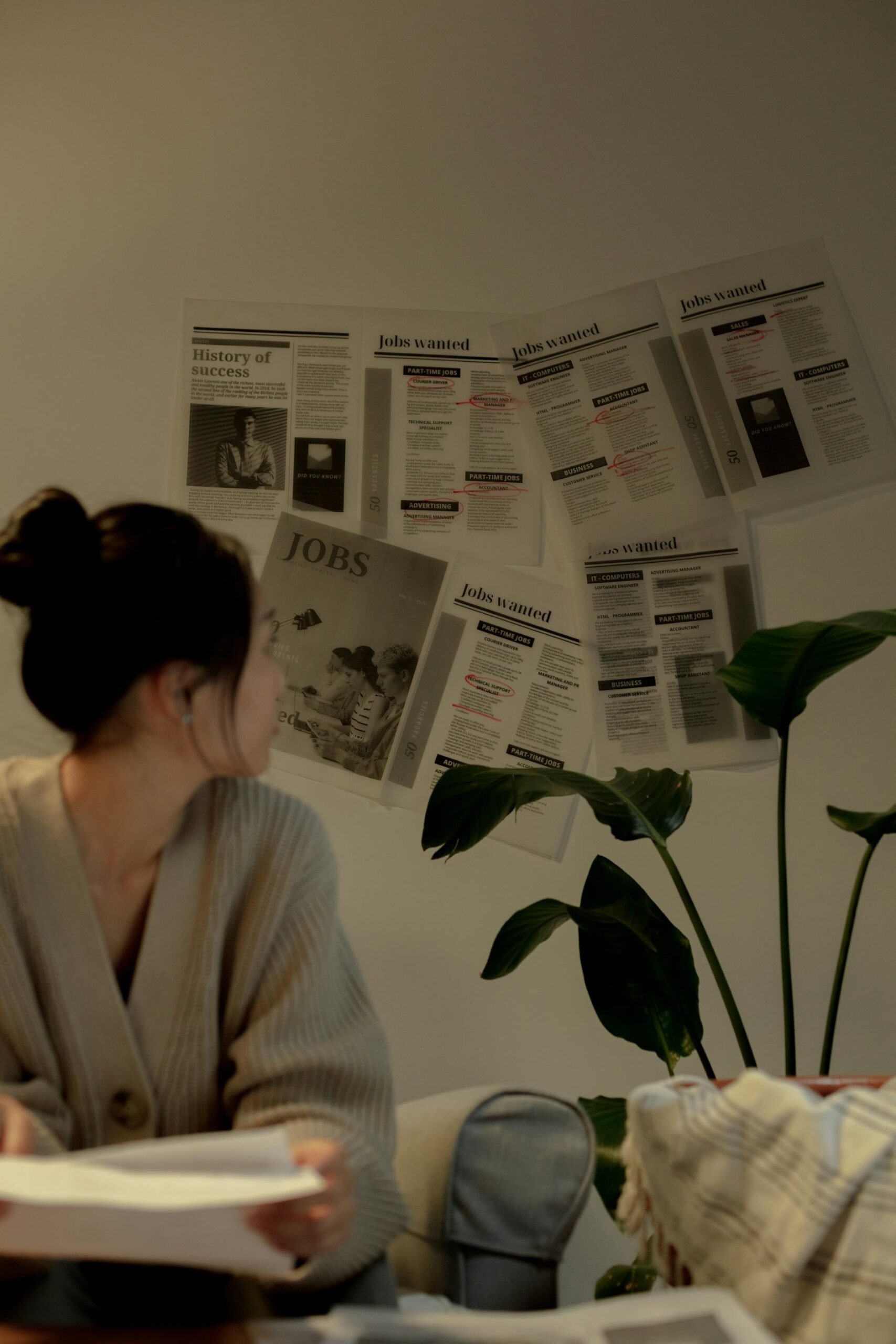 a woman sitting at a desk with job postings on the wall behind her