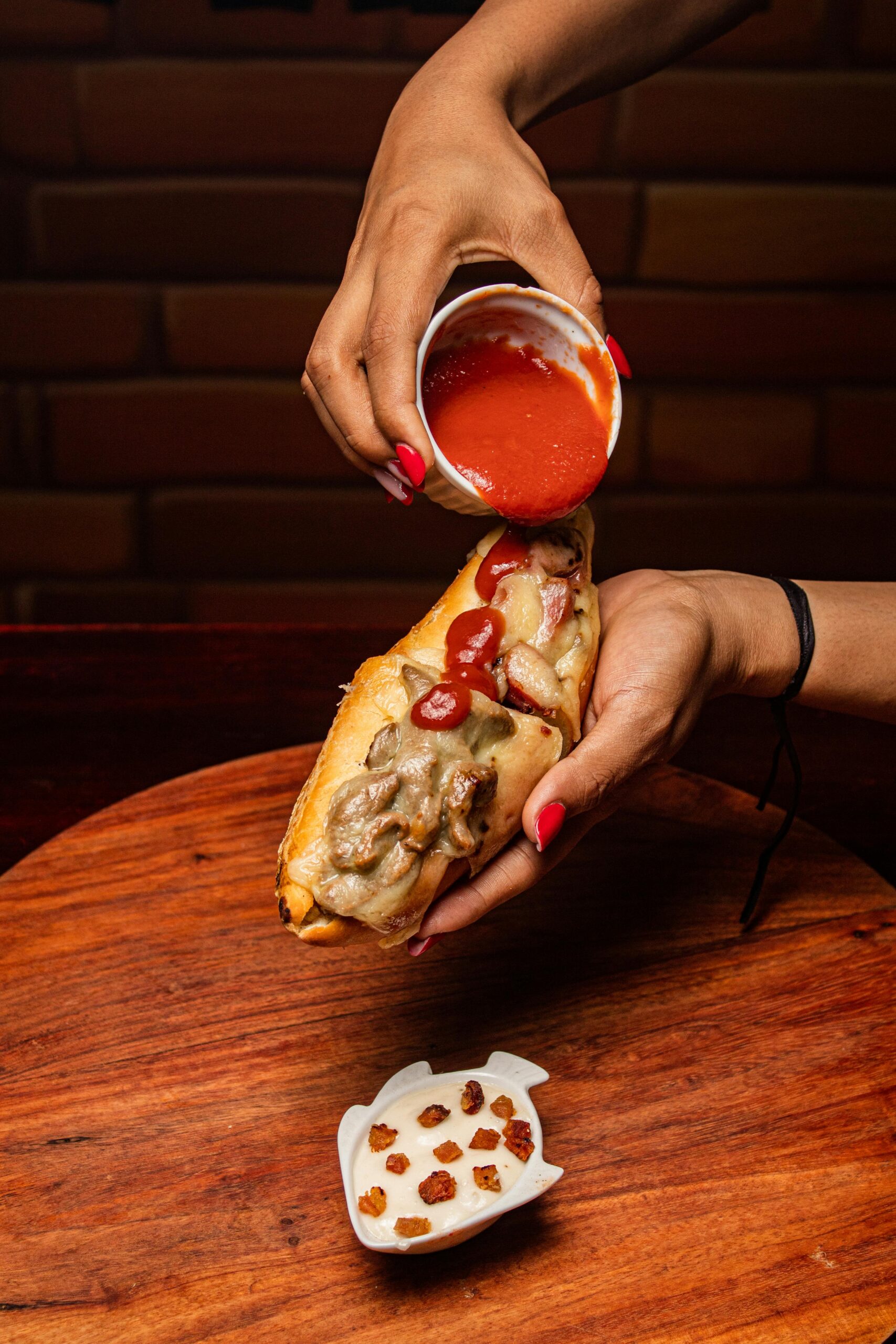 woman pouring sauce on a philly cheesesteak