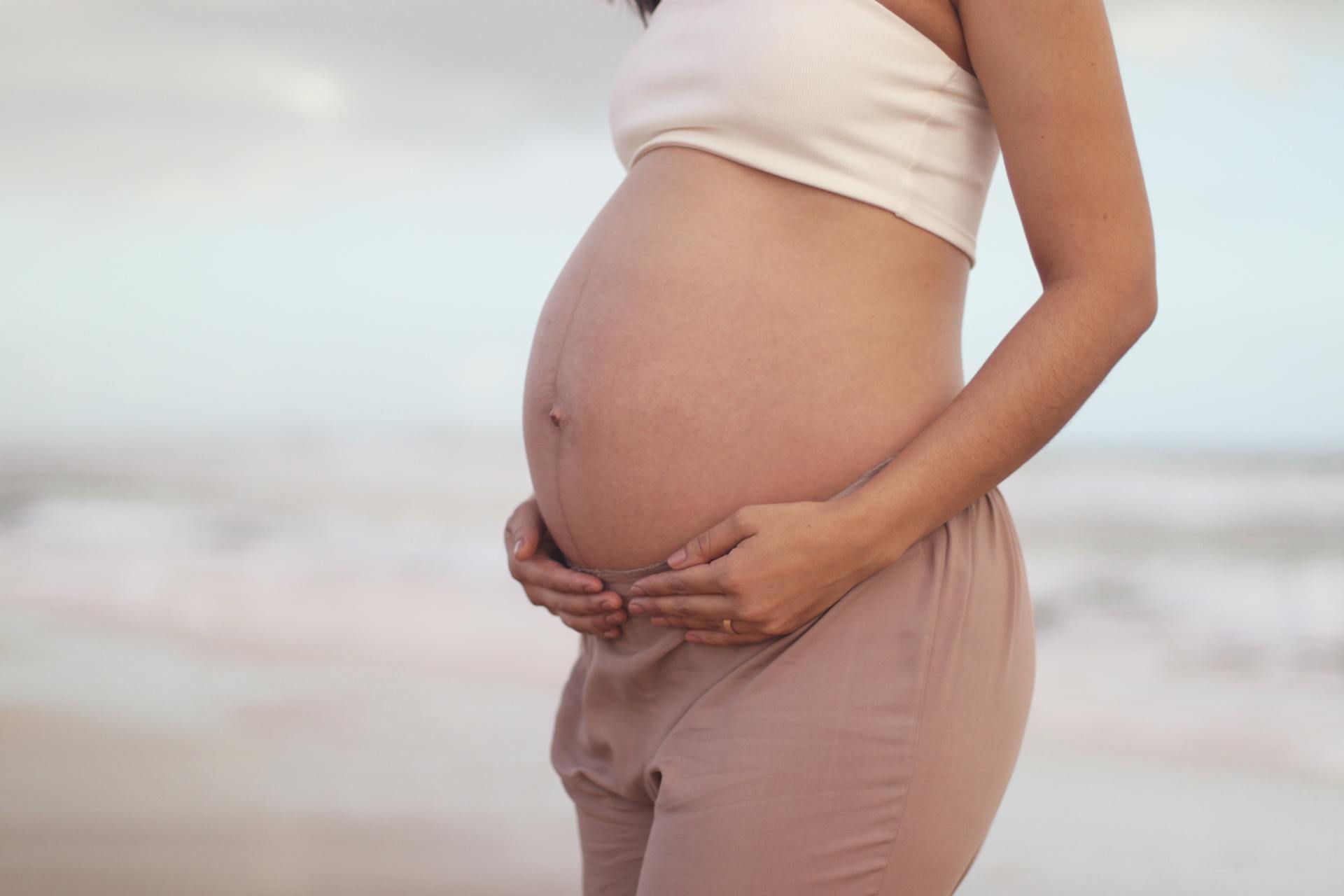 pregnant woman holding her belly on a beach
