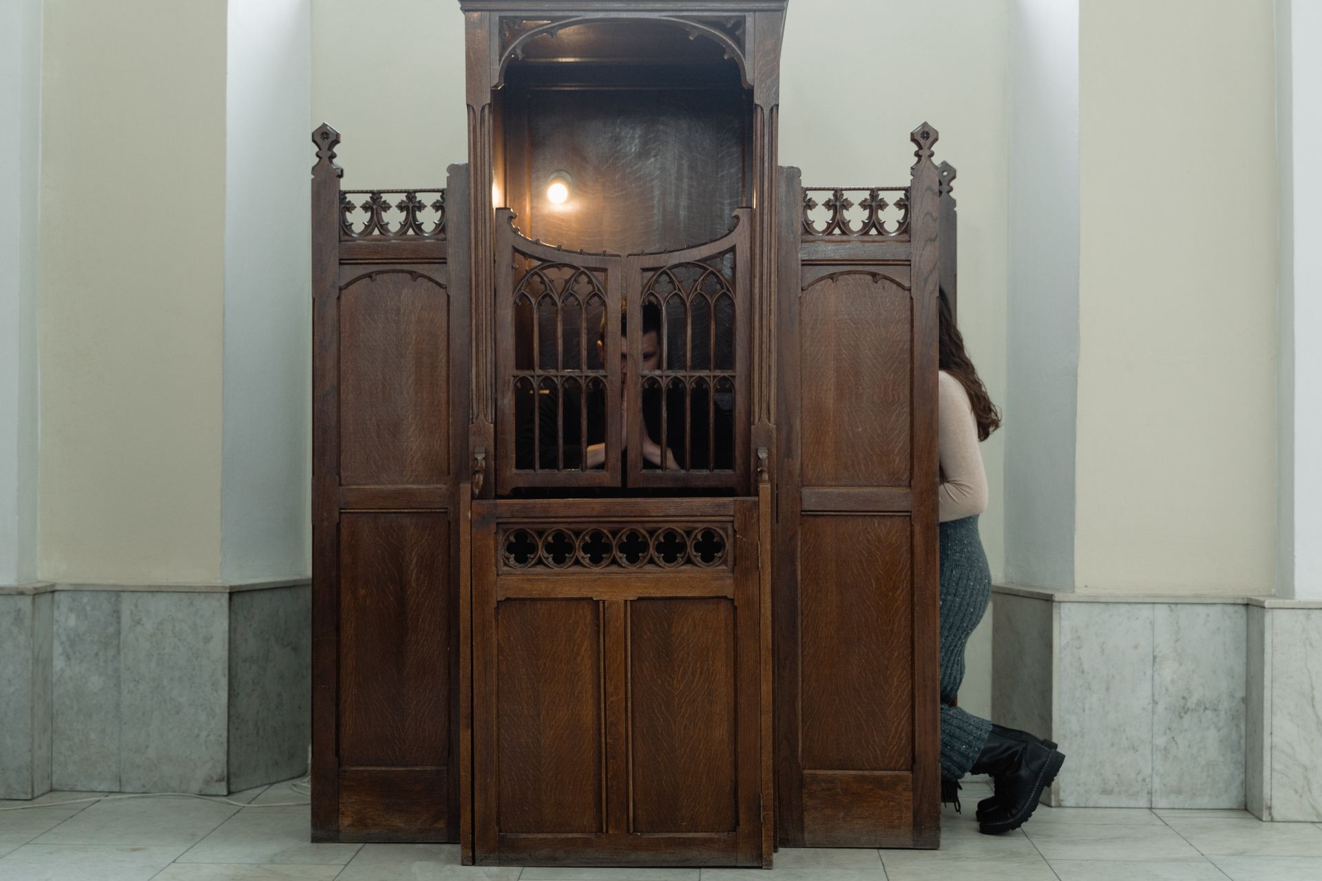 a person partially inside a confessional