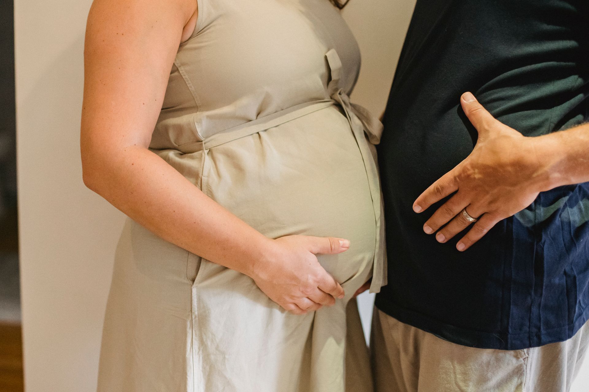 a couple holding a womans pregnant belly