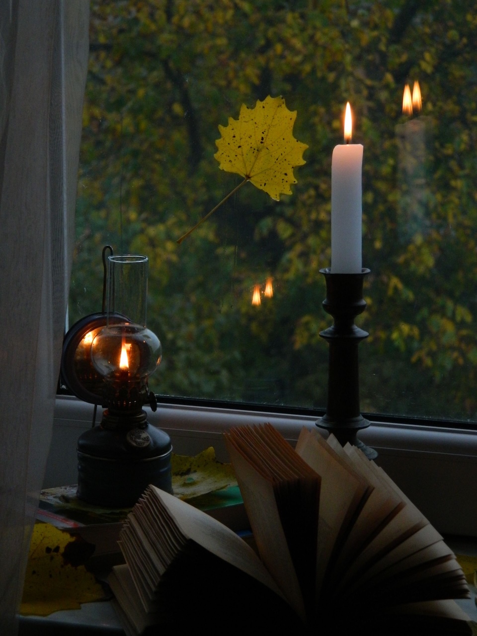 candlesticks lit in front of a dreary window during autumn