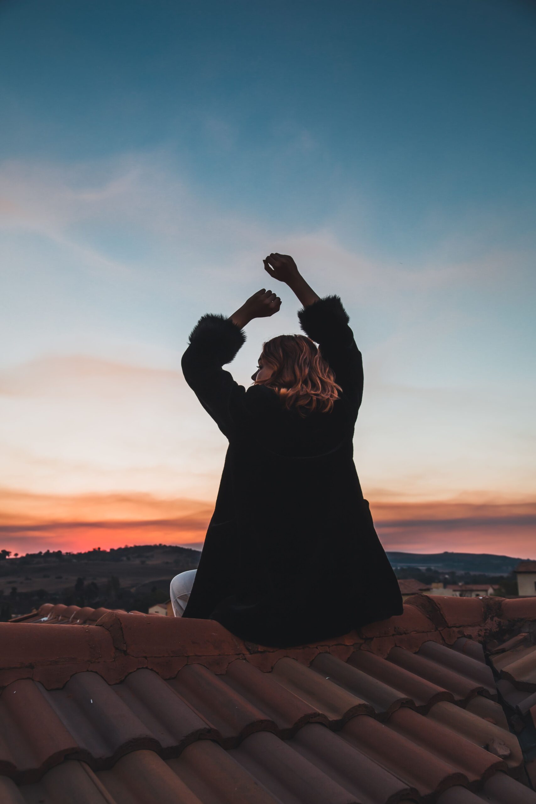 woman sitting on a roof at sunset
