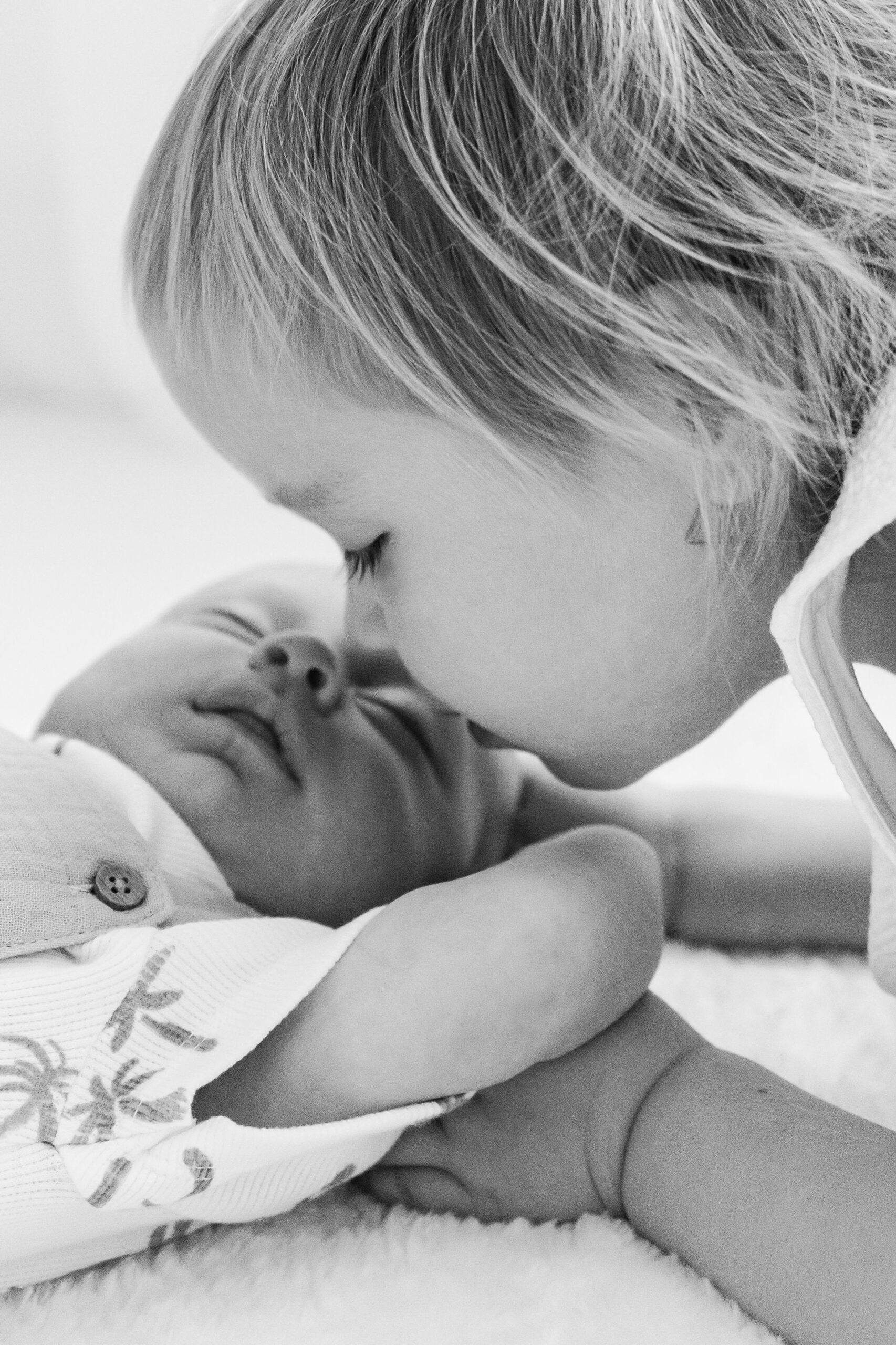 sibling kissing new baby