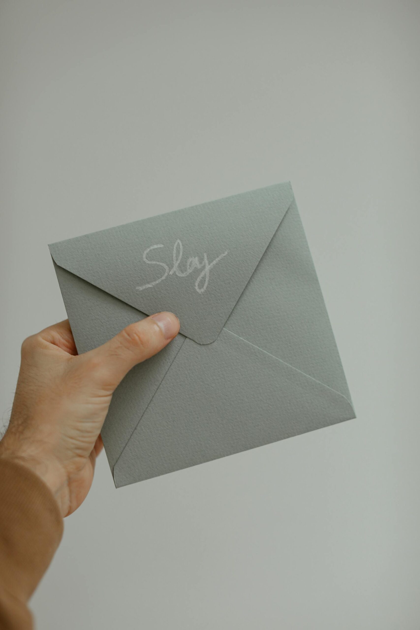 person holding an envelope with the word slay written on it