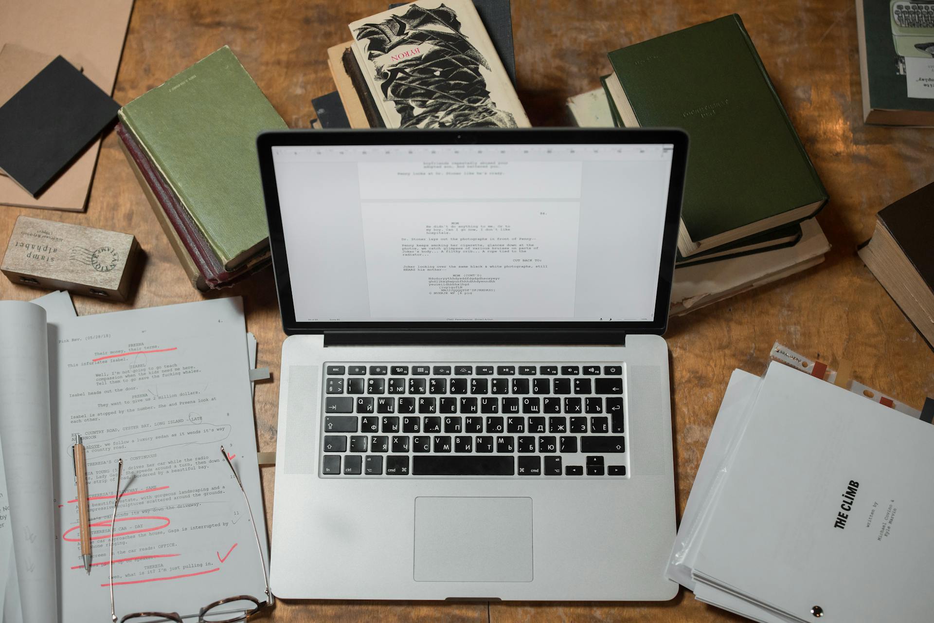 labtop surrounded by books and an edited manuscript