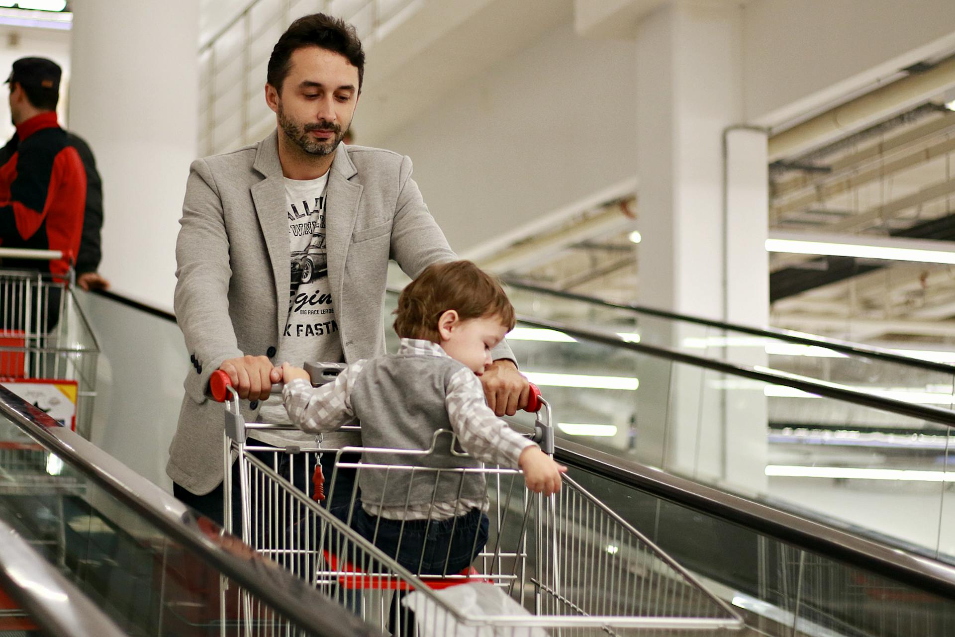 man pushes shopping cart with kid inside