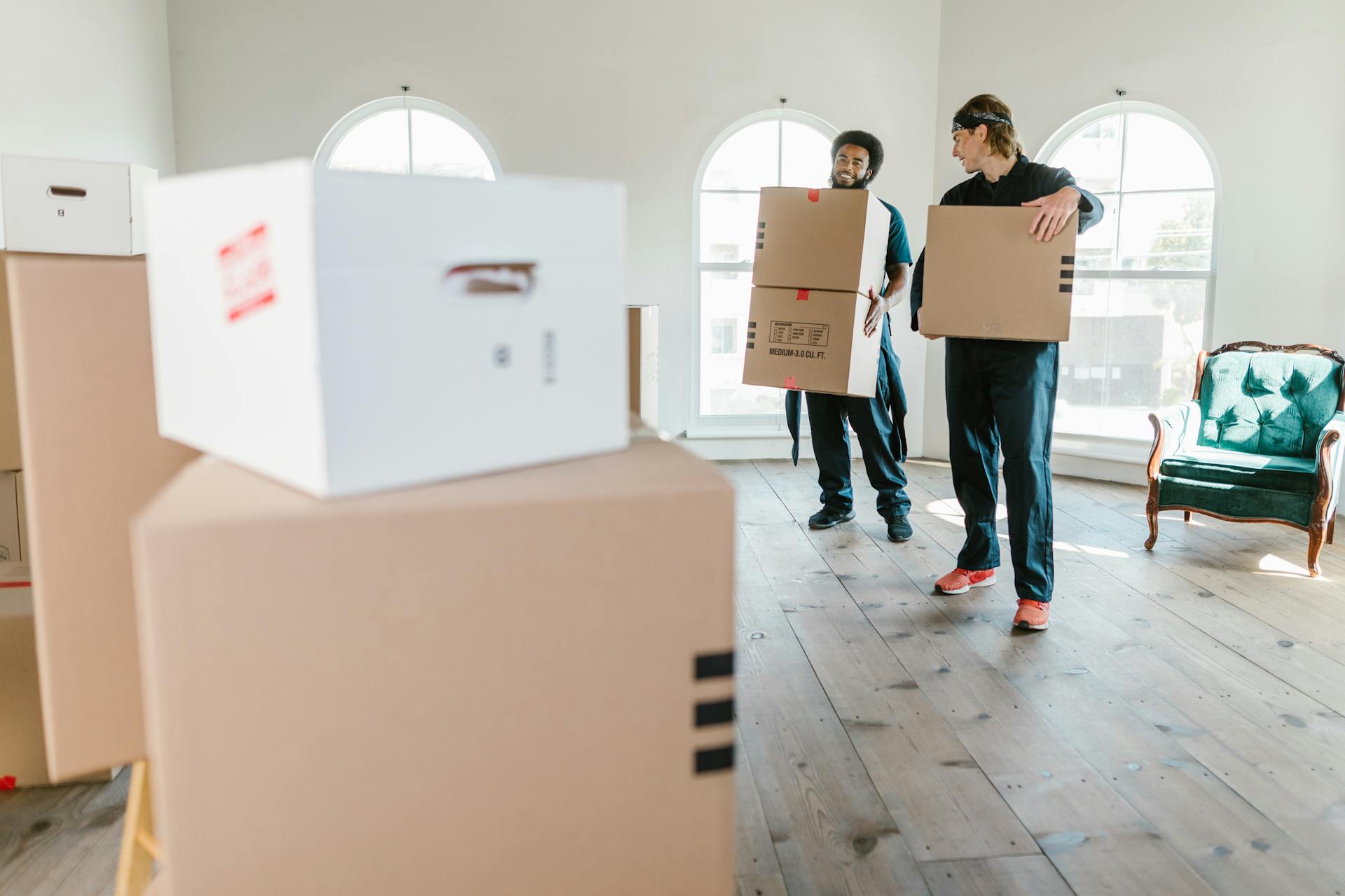 two movers carrying boxes out of a house