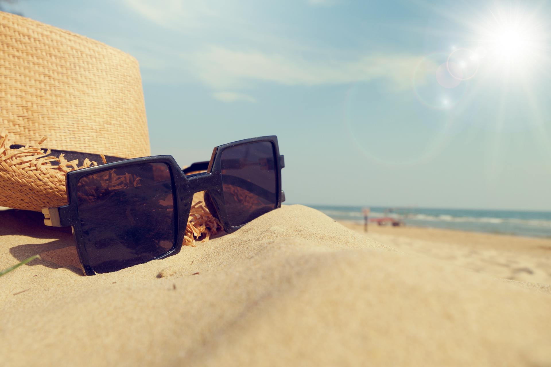 black framed sunglasses resting on the florida sand
