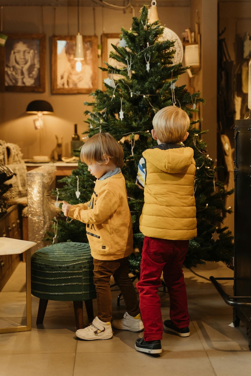 two boys standing near a christmas tree