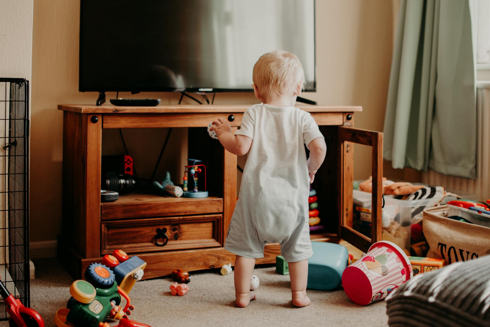 a toddler playing surrounded by toys everywhere
