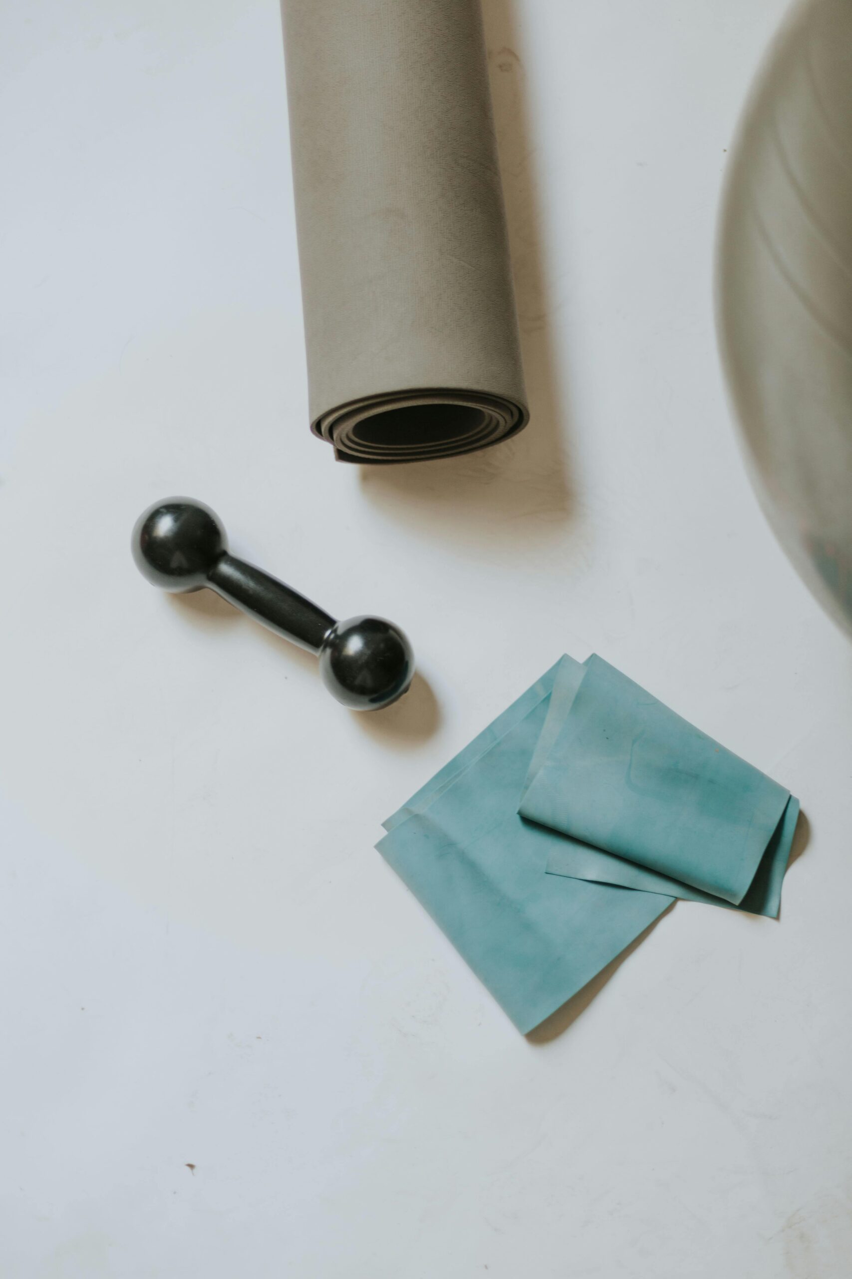 A yoga mat, resistance band, and weights placed on the floor.